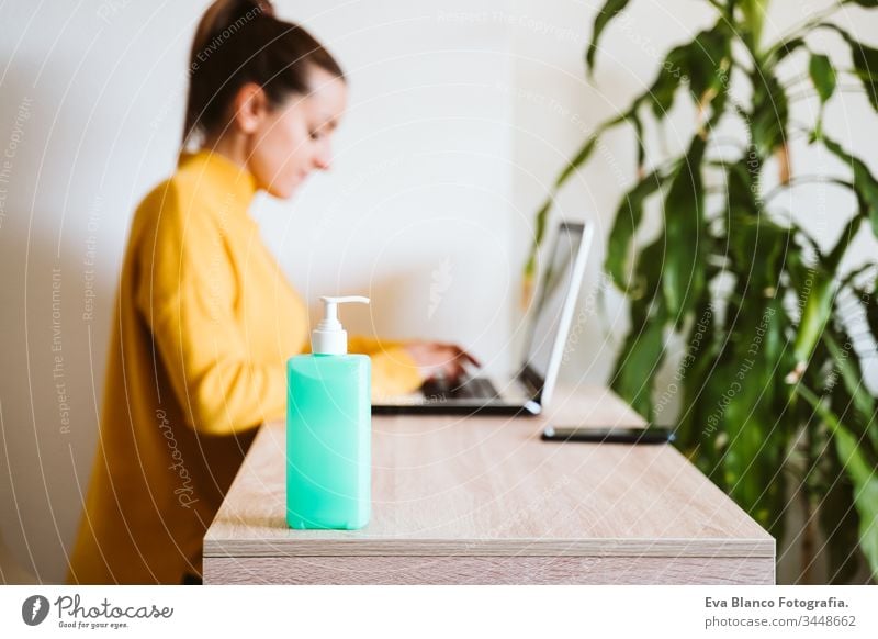 young woman working on laptop at home, using hand sanitizer alcohol gel. Stay home during coronavirus covid-2019 concept disinfectant hands antibacterial