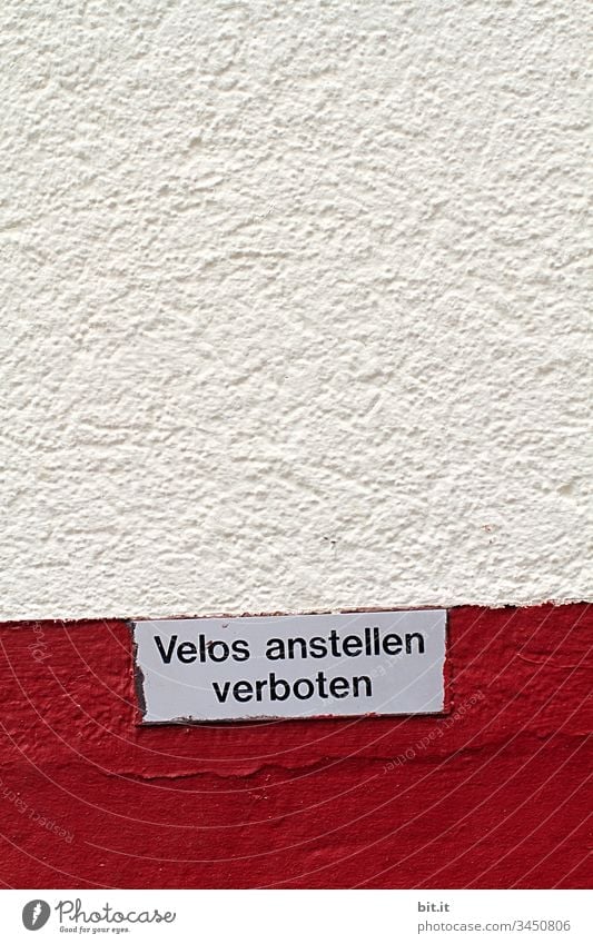 Sign on a red and white stone house wall, in Switzerland, with text: No parking for bicycles on the wall, in the city. Wheel Bike Bicycle Transport Cycling