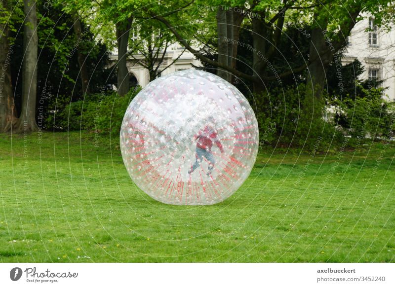 unrecognizable kid zorbing in park play playing rolling childhood plastic recreation outside globe-riding sphereing bubble fun ball sport joy activity leisure
