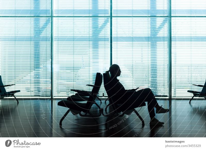 Woman in transit waiting on airport gate. waiting room waiting area lobby business passenger office hall window glass blinds time travel silhouette