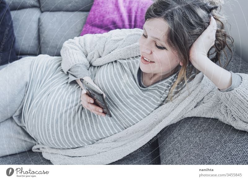 Young pregnant woman at home using her mobile phone mom work quarantine pregnancy relax technology job call text message wifi social media smart phone texting