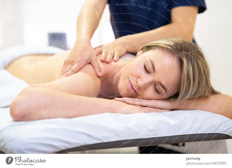Woman lying on a stretcher receiving a back massage. spa woman body beautiful treatment smile salon beauty care therapy young female relaxation girl health