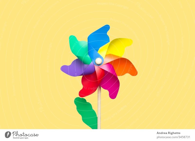 Concept of LGBT, lesbian and gay people, nostalgic childhood, rainbow flag. Rainbow pinwheel at the center of the image with a yellow background. Isolated