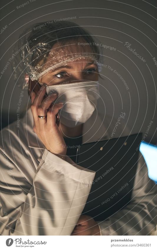 Doctor making a phone call. Hospital staff working at night duty. Woman wearing uniform, cap and face mask to prevent virus infection doctor flu ill sick care
