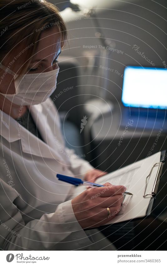 Doctor filling out a document. Hospital staff working at night duty. Woman wearing uniform, cap and face mask to prevent virus infection doctor flu sick care