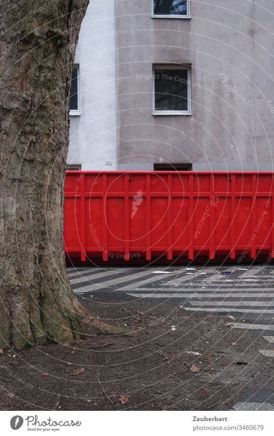 Red container stands in front of a dull house facade with empty window, in front of it a tree Container Tree Tree trunk House (Residential Structure)