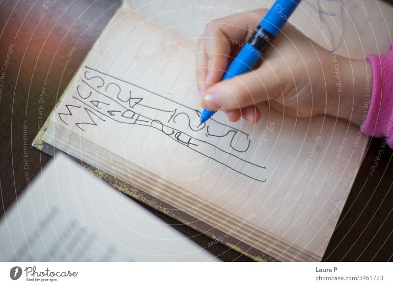 Close up of a child hand writing in a notebook adorable attentive attentively beautiful blonde bored caucasian childhood clever closeup concentrated cute doing