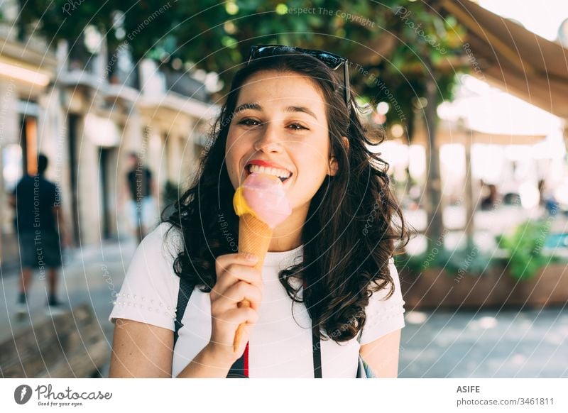 Young tourist woman enjoying an ice cream while exploring the city travel vacation girl eating scoop cone refreshment holiday snack food happy backpack camera