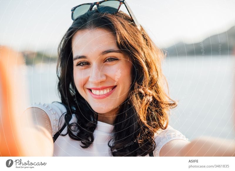 Happy beautiful young woman making a selfie by the sea in summer portrait self portrait toothy cheerful face happy joy close up girl holiday vacation travel