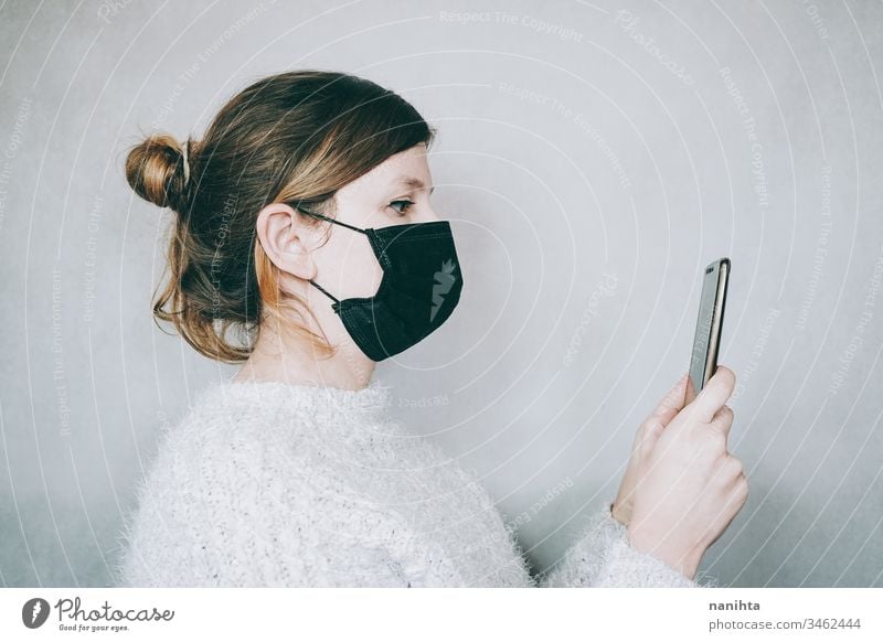 Young woman wearing a mask while use her smartphone covid 19 coronavirus breath pandemic illness infected mobile news fake news social media technology