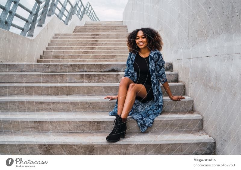 Afro-american woman sitting on steps. afro grey young girl face wall expression adult looking fashion black standing smiling confident hair brunette model