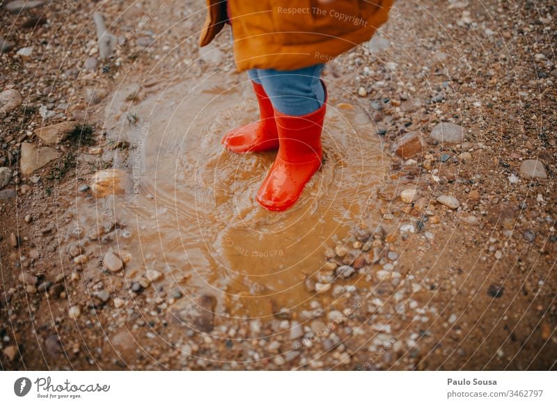 Feet of child in red rubber boots over a puddle Red Rubber boots Boots Rain Child Wet Exterior shot Weather Colour photo Puddle Human being Joy Water Dirty