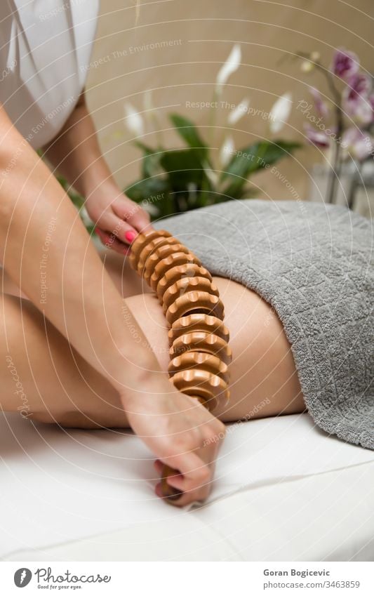 Maderotherapy anti-cellulite massage with wooden roller massager adult body care deep female hand handle health healthy leg legs lifestyle lying madero
