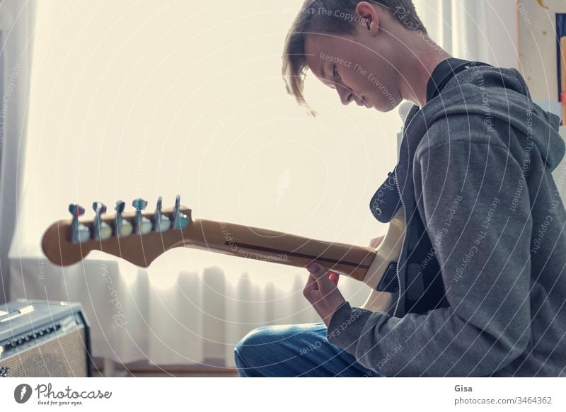 Male teenager plays an electric guitar in his room. Guitar Electric guitar Fantasy Sunlight Youth culture Window Room Quarantine covid-19 Virus Creativity