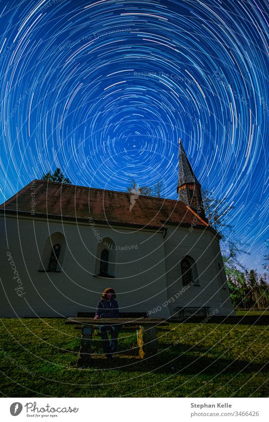 Clear sky star night, long exposure photo with circle star trails polaris in focus and a chapel in foreground. church stars startrails selfie man person