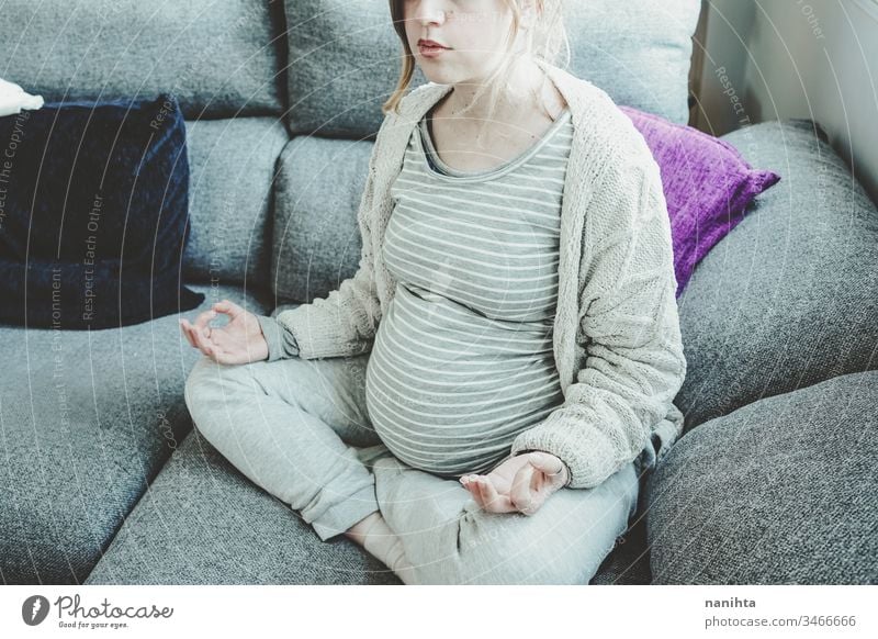 Young pregnant woman doing yoga at home pregnancy mom family quarantine relaxation meditation peace stay at home lying care self sofa relaxing pretty face