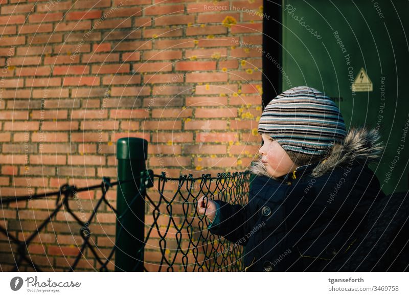 little boy looks into the distance Toddler Boy (child) Observe Wire netting fence look see search. look look look afar look away wander far and wide