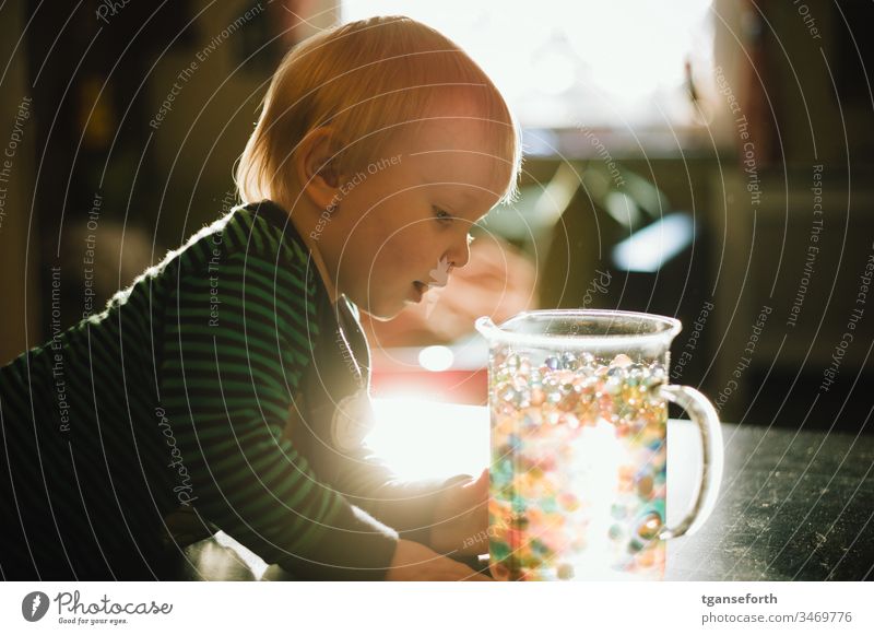 little boy discovers colorful beads Boy (child) Colour photo Child Portrait photograph Trickle Lighting effect Discover Study explore Enthusiasm Playing