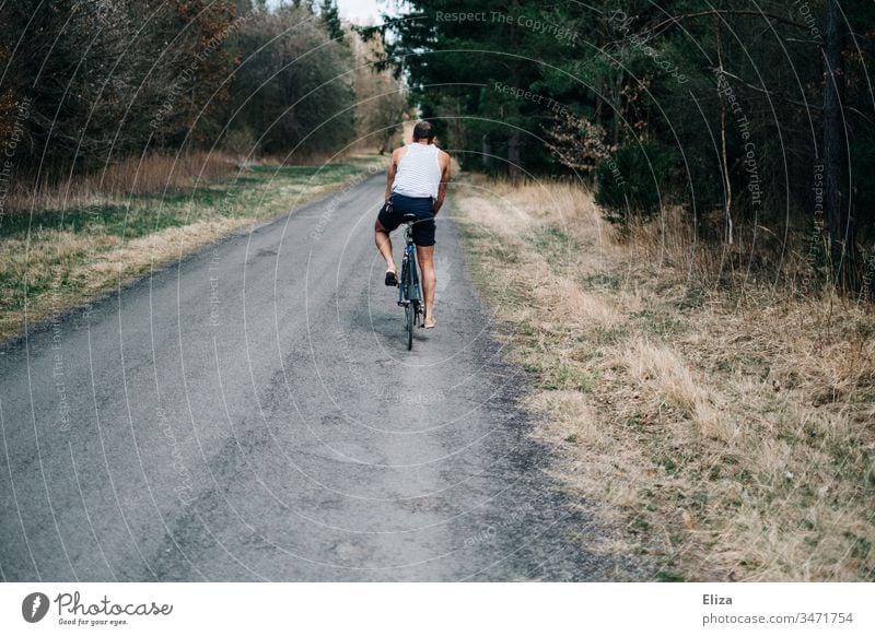 Young man on a bicycle riding a road through the forest Bicycle Cycling cyclist Man Freedom Summer Street off Forest Sports Exterior shot Leisure and hobbies