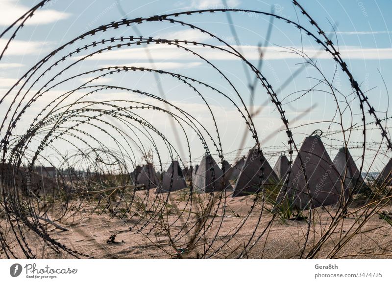 barbed wire and concrete military fence on the beach near the sea in Crimea Russia Ukraine annexation army ban barrier blue border closed closed territory