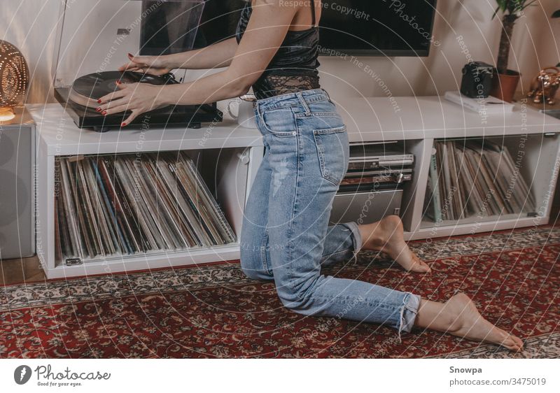 Young woman putting a vinyl record on. album analog audio barefoot beautiful beauty black top blond bohemian boho lifestyle casual caucasian entertainment