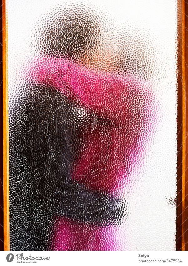 Couple hugging behind closed door glass window couple woman girl in love hugs cinema story arms kiss passion art voyerism through authentic see silhouette pink