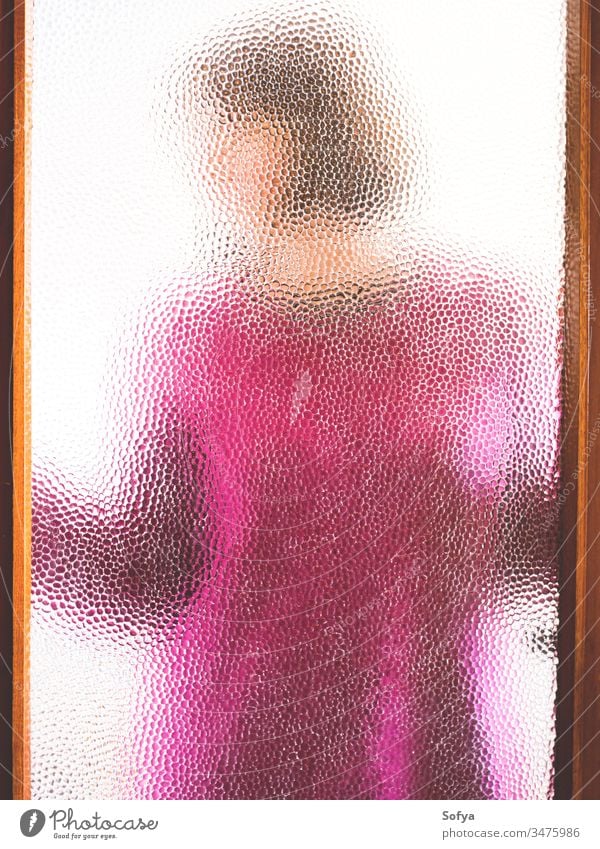 Young woman behind closed door seen through glass girl stay home window silhouette pink sweater winter cozy stay safe coronavirus covid19 isolation alone