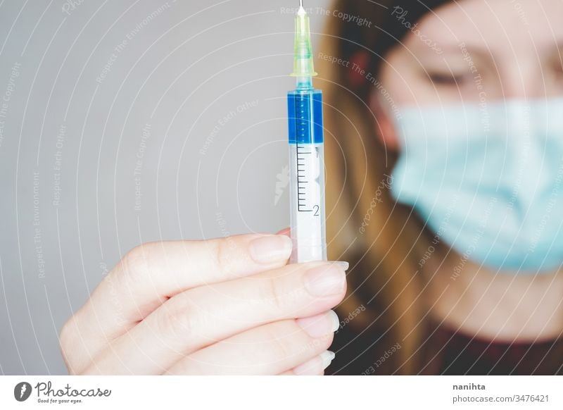 Young woman wearing a face mask and hold a vaccine covid 19 flu influenza coronavirus pandemic epidemic investigation studio treatment medicine drug syringe