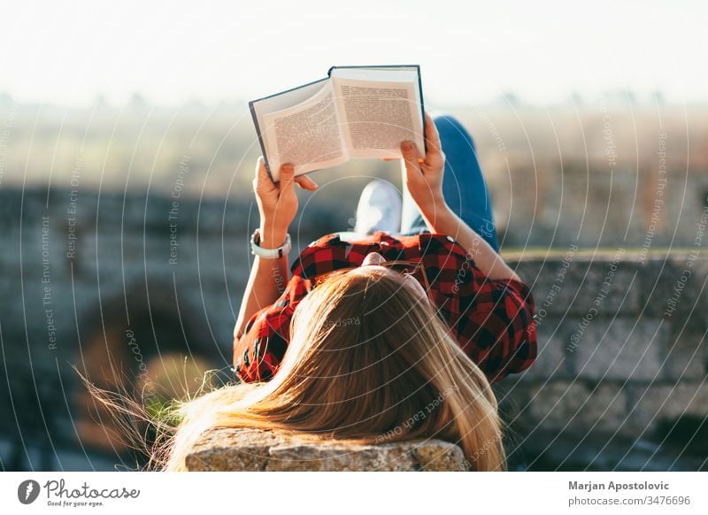 Young woman reading a book outdoors young outside joy studying student enjoying lifestyle spring summer lying leisure girl female people person adult caucasian