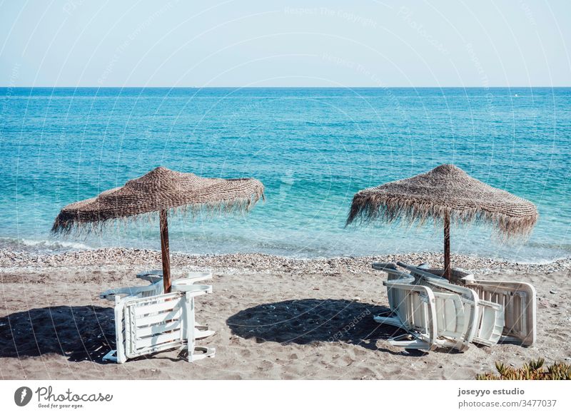 Umbrellas and empty deckchairs collected on the beach shore in summer. background beach chair blue coast coastline coronavirus covid-19 deck chair empty beach