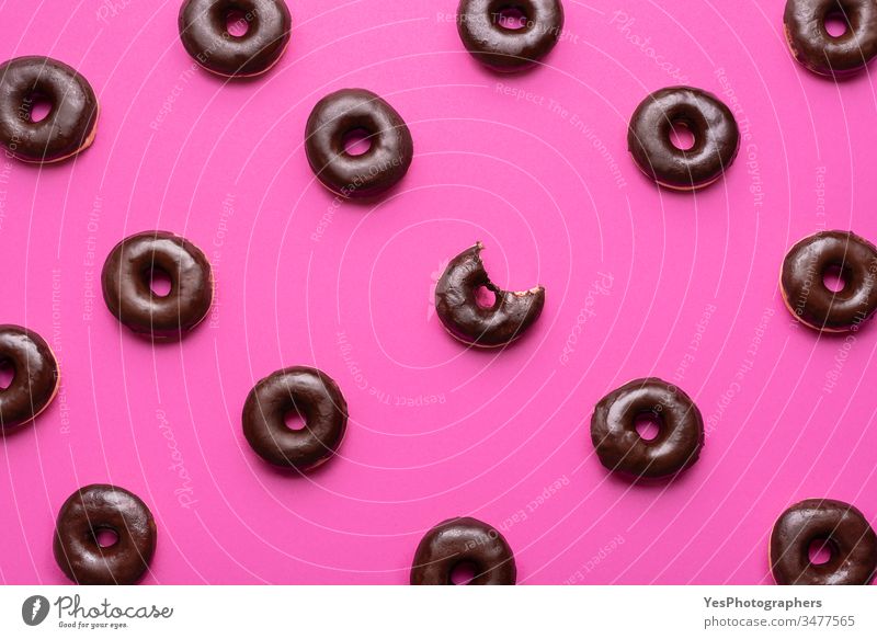 Chocolate glazed donuts pattern. One doughnut with a missing bite above view alligned background bagel bakery bitten calories carbs choco choco donuts chocolate