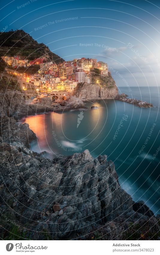 Amazing landscape with small town with colorful lights on rocky coast washing by tranquil ocean water at night sea idyllic cliff sky shore paradise tourism city