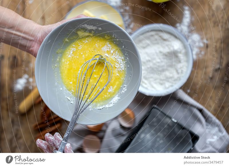 Faceless woman preparing eggs with whisk in kitchen cook ingredient bowl wooden table process food prepare cuisine fresh recipe delicious nutrition culinary