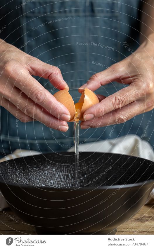 Crop woman breaking egg into bowl cook pastry fresh female fragile eggshell ingredient food cuisine recipe organic gourmet homemade wooden table raw add dough