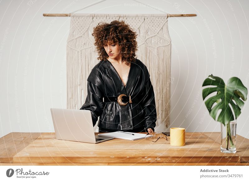 Vintage businesswoman using laptop on table office work leather jacket sit retro style outfit female cool project startup 80s fashion device gadget browsing