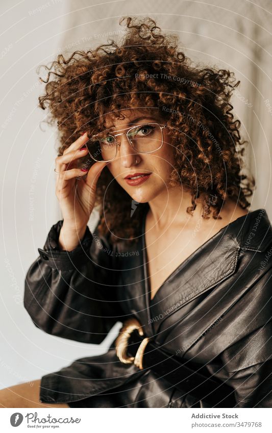 Retro female entrepreneur adjusting glasses businesswoman retro smart leather jacket style work adult curly hair outfit dress elegant fashion trendy 80s