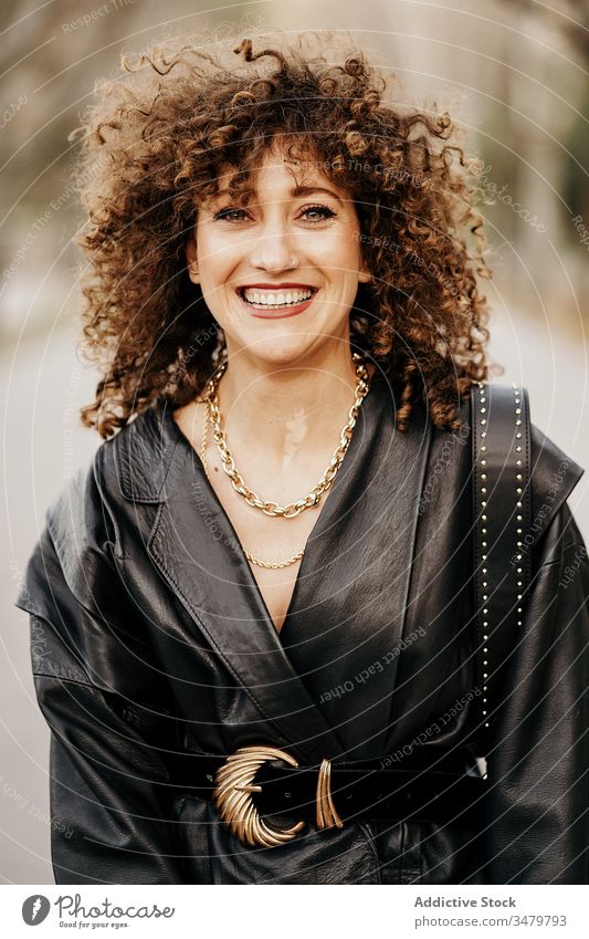 Delighted retro businesswoman on street city smile leather jacket adult curly hair commute work outfit style happy female delight optimist model fashion trendy