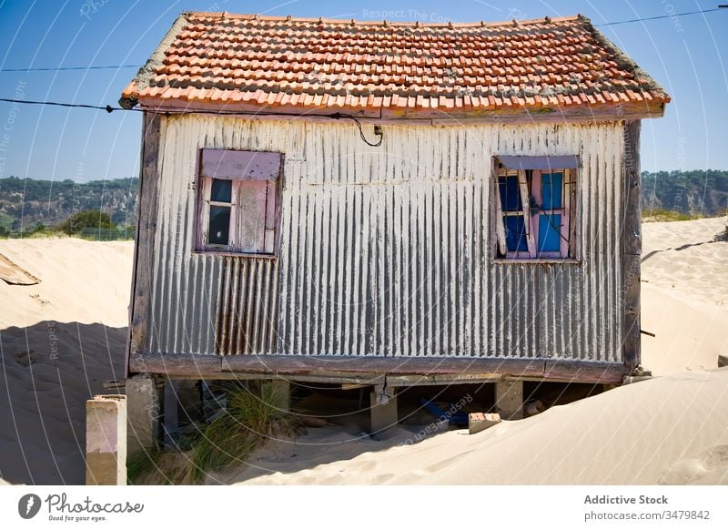 Old shabby house on sandy beach small coast building facade rural countryside exterior architecture sunny blue sky construction structure residential window