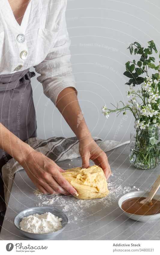 Crop woman kneading dough on table pastry cook flour apple sauce flower female bouquet apron kitchen prepare food ingredient sourdough cuisine recipe chef soft