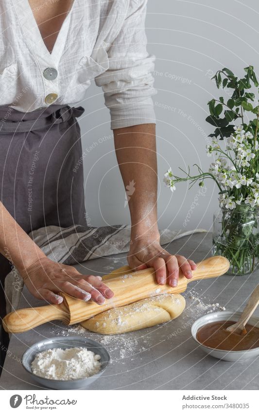 Crop female rolling pastry dough woman cook rolling pin table flour apple puree flower bouquet apron tool utensil kitchen prepare food ingredient cuisine recipe
