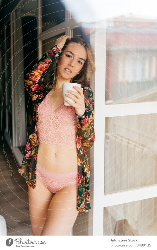 Woman in lingerie drinking coffee at home woman morning window happy young attractive female pretty enjoy slim smile cheerful underwear mug balcony apartment