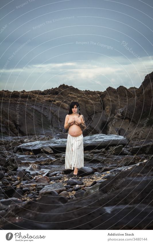 Sensual pregnant woman on remote rocky shore nature sensual topless maternal natural connection landscape serene harmony expect childbirth body parent mother