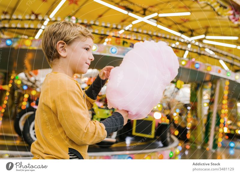 Boy eating cotton candy on funfair boy candyfloss smile lights city entertainment kid happy child urban sweet delighted treat lifestyle cheerful little sugar
