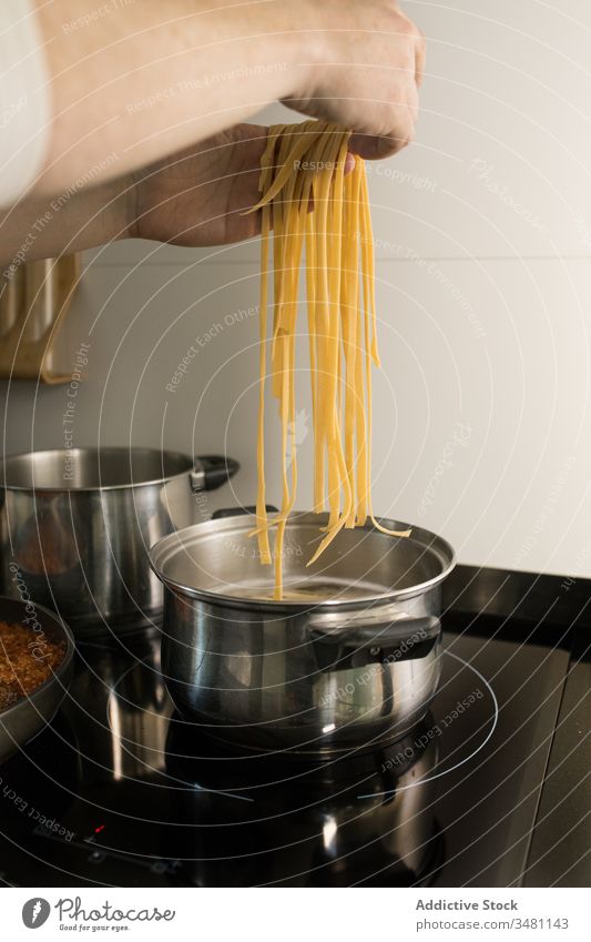Cook putting spaghetti into pan with boiling water pasta prepare noodle saucepan hand homemade kitchen cook food cuisine culinary meal dinner recipe fresh