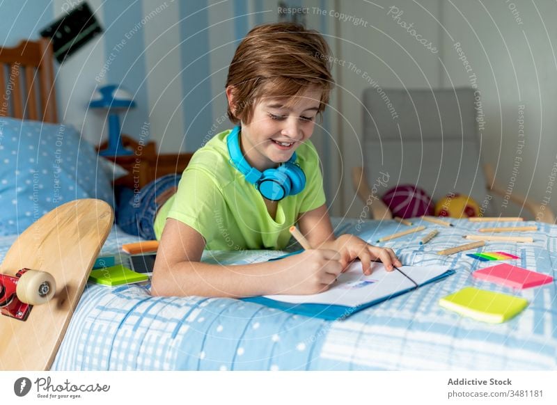 Little boy drawing and listening to music in bedroom kid headphones cheerful home chill happy colorful pencil wireless smile lifestyle child joy education learn