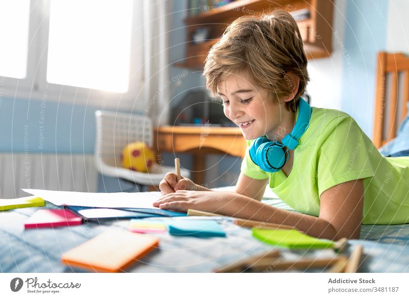 Little boy drawing and listening to music in bedroom kid headphones cheerful home chill happy colorful pencil wireless smile lifestyle child joy education learn