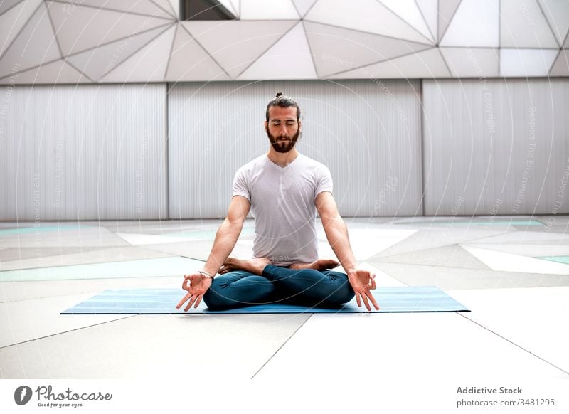 Bearded man meditating during yoga training meditate lotus pose geometry eyes closed healthy exercise relax male fitness workout legs crossed sportswear