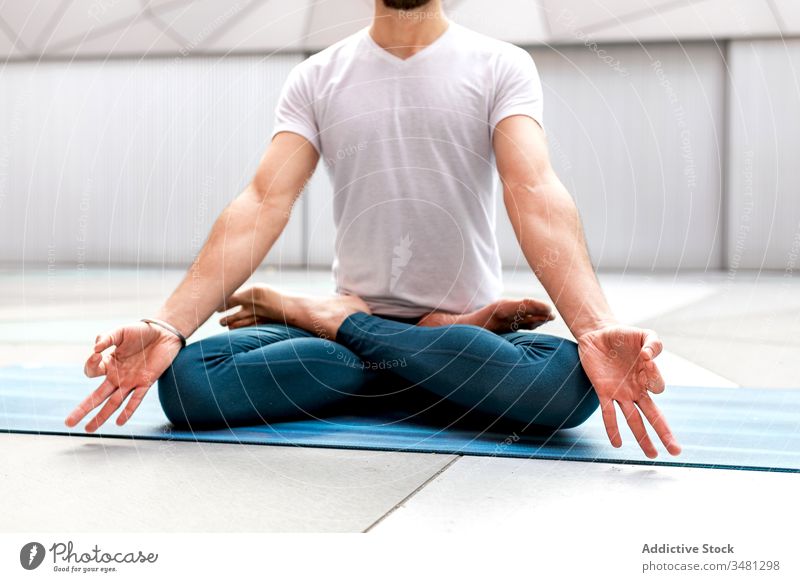 Anonymous man meditating during yoga training meditate lotus pose geometry healthy exercise relax male fitness workout legs crossed sportswear lifestyle athlete