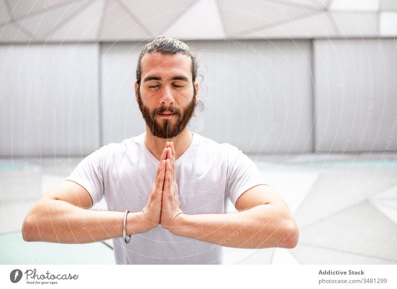 Bearded male meditating with clasped hands man meditate yoga training geometry eyes closed hands clasped healthy exercise relax fitness workout sportswear
