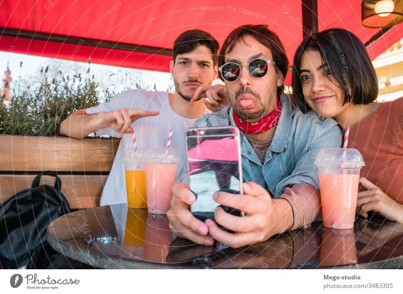 Three young friends taking a selfie with phone. happy fun together hangout four leisure looking person sitting enjoyment happiness smartphone relationship